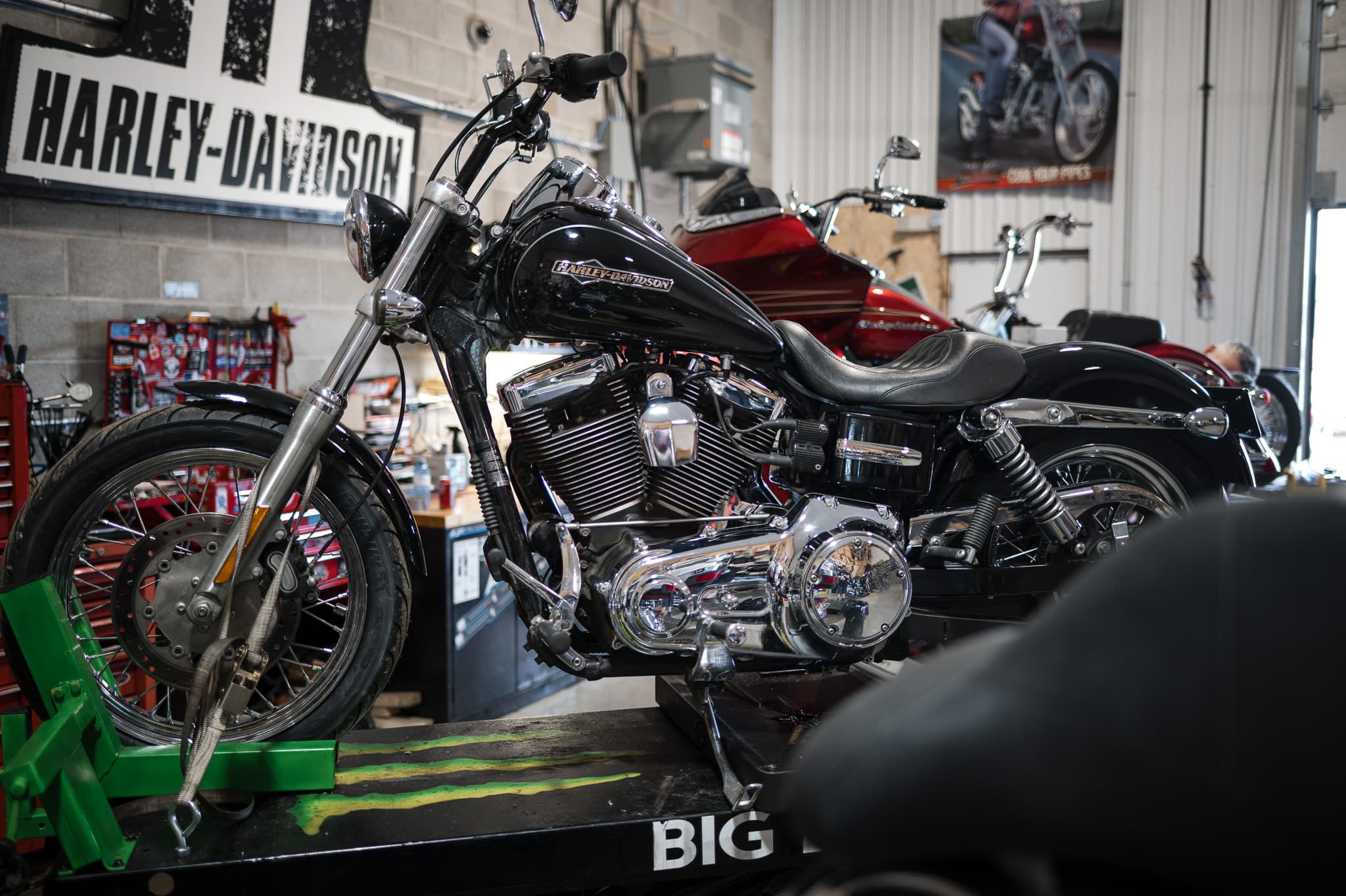 Black Harley-Davidson Dyna on the Big Bear lift in front of the shop's Harley-Davidson sign
