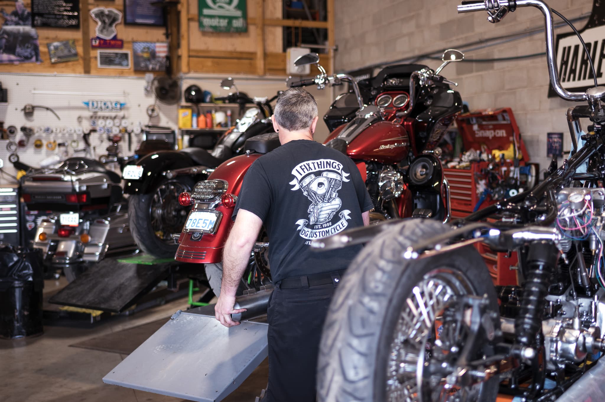 Technician working in the busy DG Custom Cycle service bay with several Harleys in for work