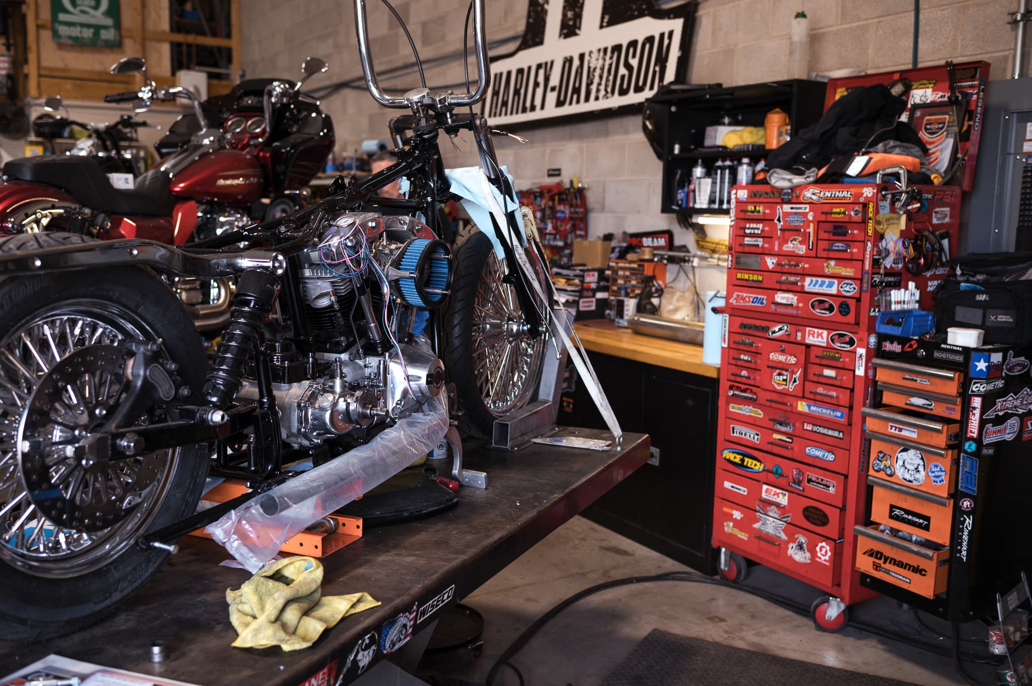 Hardtail chopper torn down on the lift with the Snap-on toolbox and Harley-Davidson sign behind