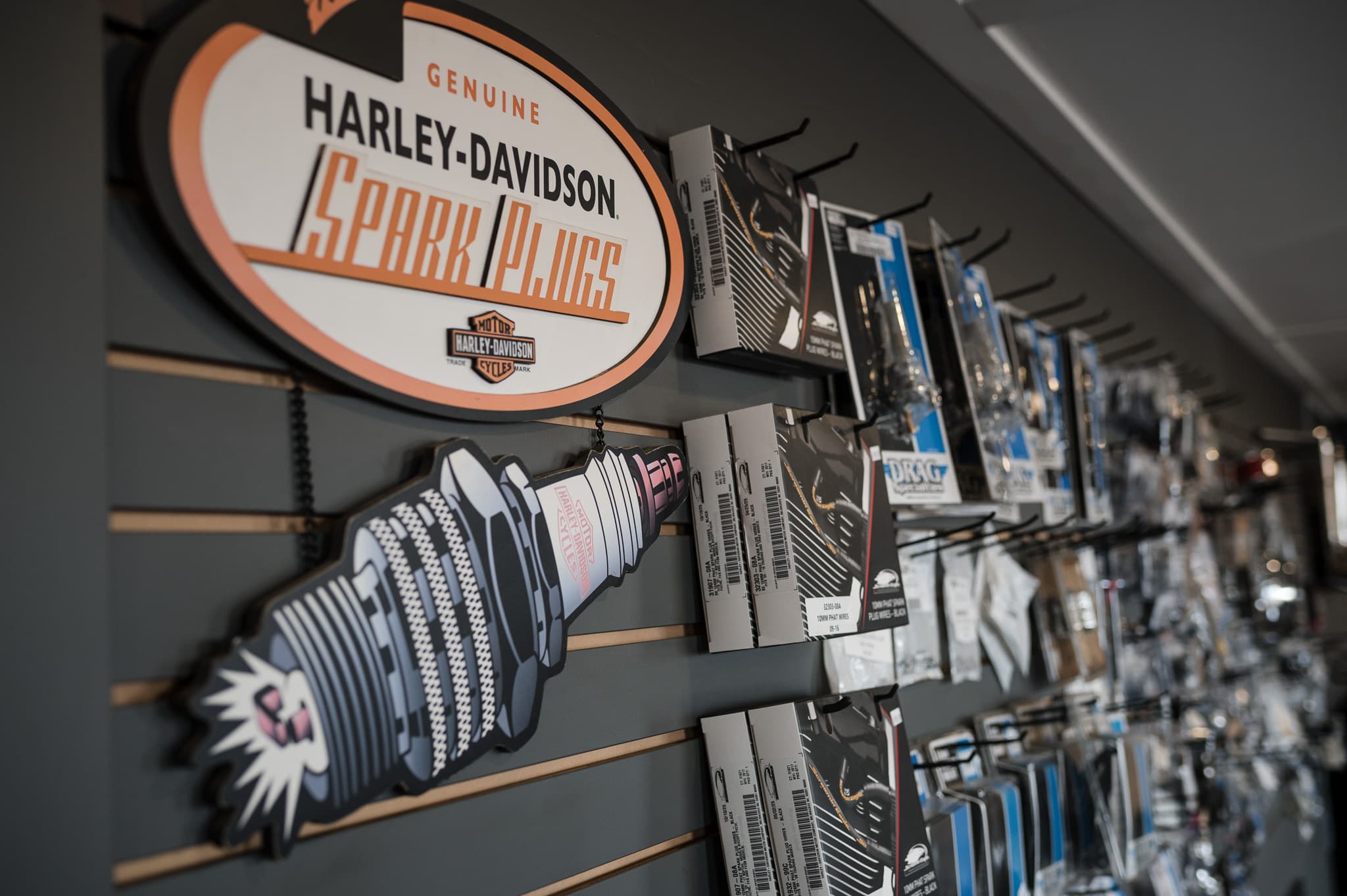 Genuine Harley-Davidson spark plugs sign above the parts wall at DG Custom Cycle
