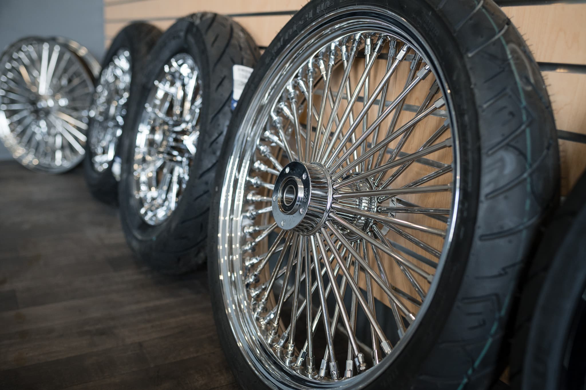 Lineup of chrome-spoked Harley wheels and tires staged against the showroom wall