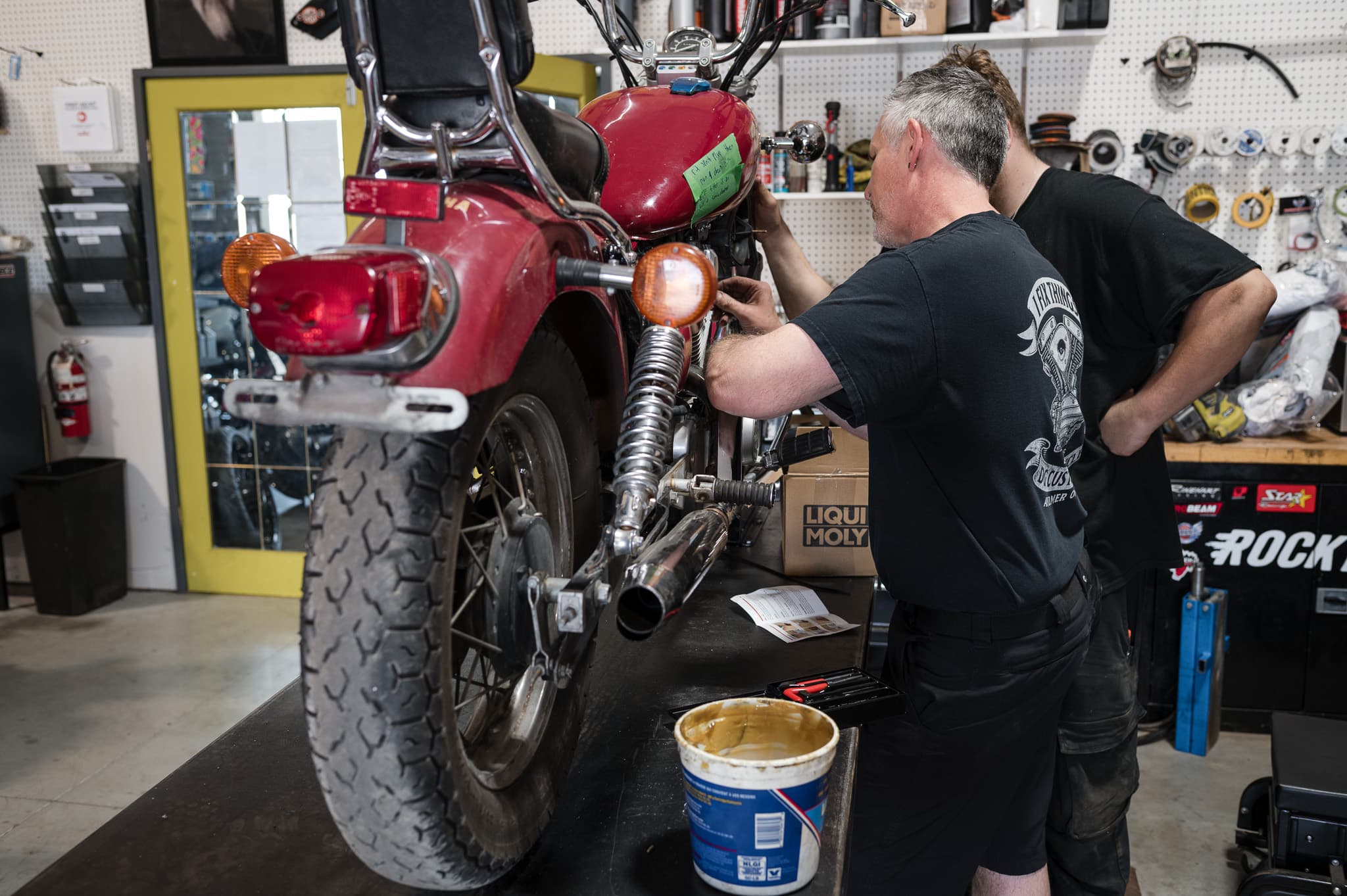 DG Custom Cycle technician working on the rear end of a Harley in the service bay