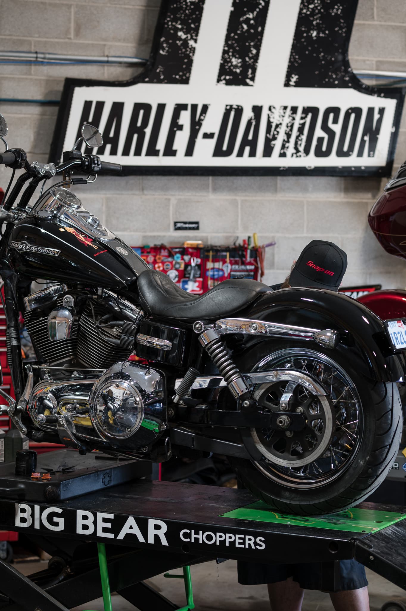 Harley-Davidson Dyna up on the service lift beneath the shop's Harley-Davidson sign