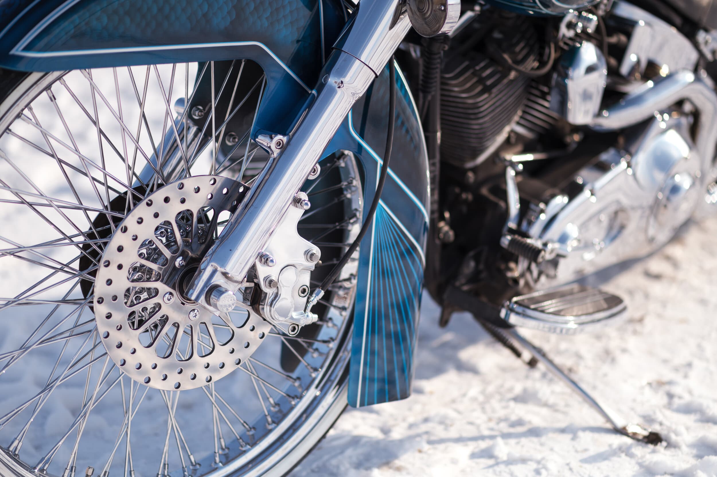 Front wheel and brake rotor of a Harley resting on snow-covered ground